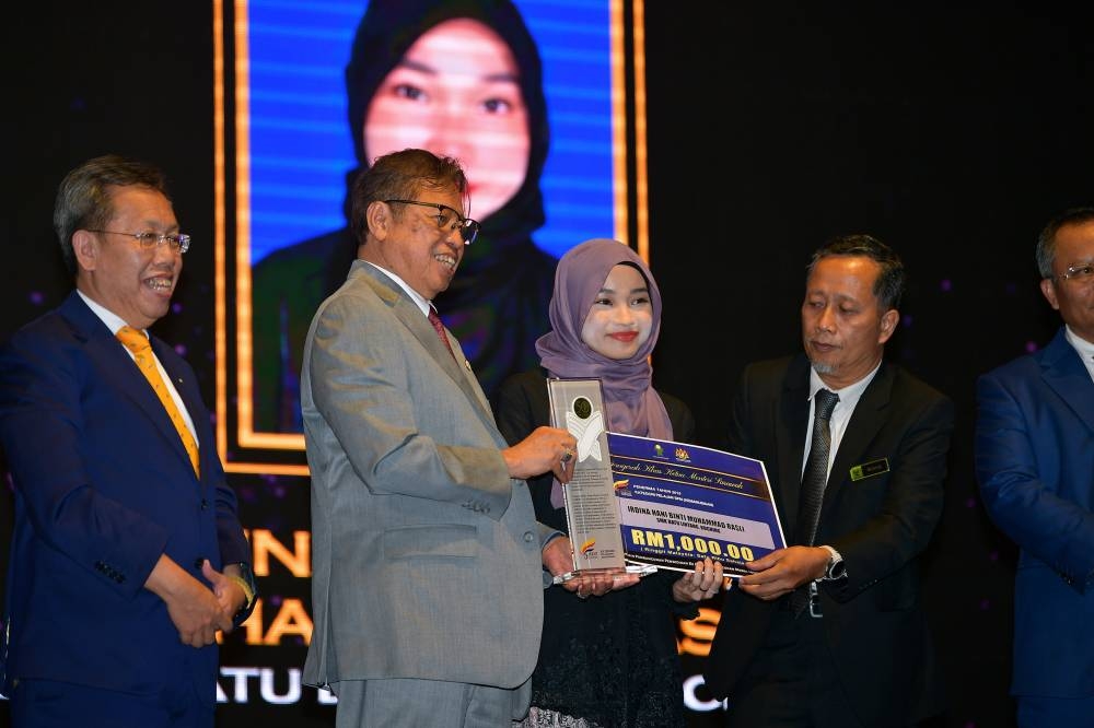 Sarawak Premier Tan Sri Abang Johari Openg (2nd left) presents a trophy and mock cheque to SMK Batu Lintang Kuching student Irdina Hani Muhammad Rasli under the SPM category at the launching of the 30th Sarawak Premier Special Award ceremony in Kuching September 14, 2022. — Bernama pic