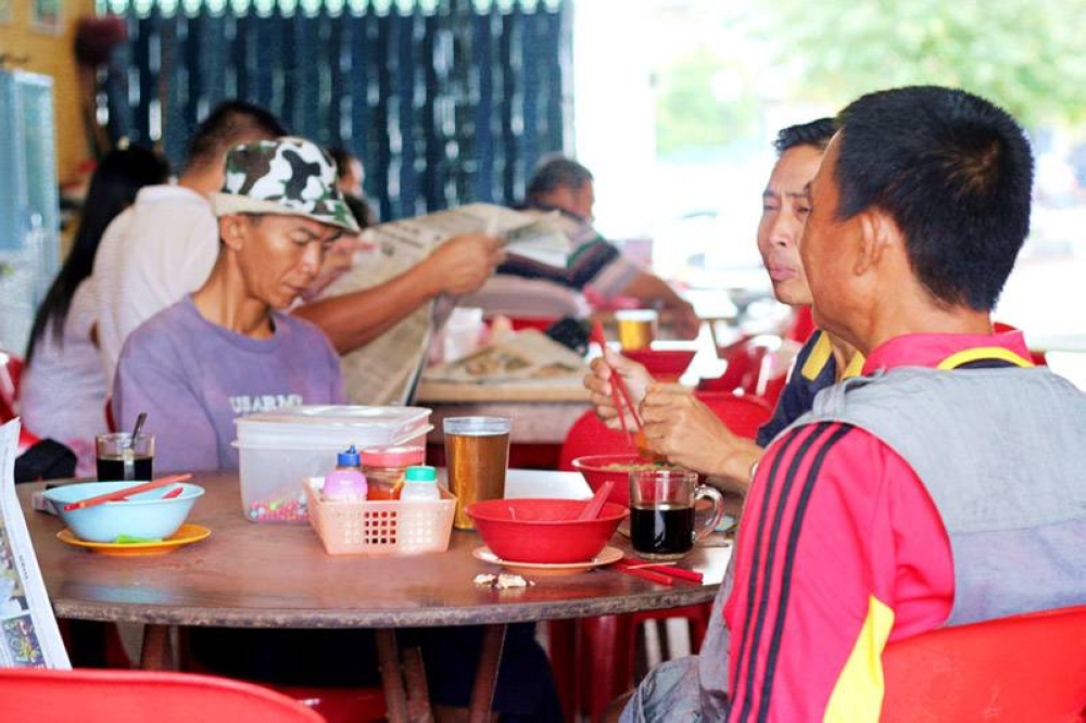 Customers at a local 'kopitiam' sharing food and conversations, most of them long-time regulars.