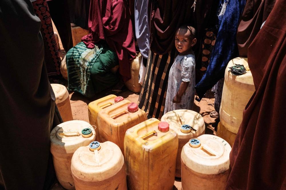 People wait to fill their water tanks as they receive water delivery by the Save the Children twice a week in Kubdisha on September 1, 2022. — AFP pic