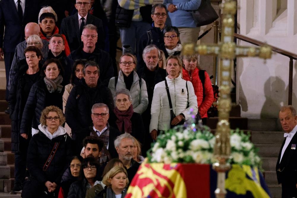 Visitors get their first glimpse of Queen Elizabeth II's flag-draped casket lying in state on the catafalque as they enter Westminster Hall on September 17, 2022 in London, England. — Reuters pic