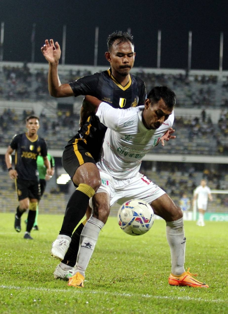 Perak FC player Muhammad Farid Khazali (left) is blocked by Kuching City's Rames Lai Ban Huat during the match in Ipoh September 17, 2022. — Bernama pic