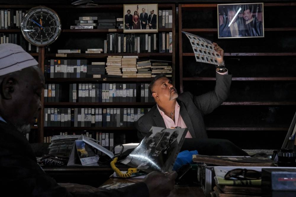 Salim Amin (right) son of the late photographer Mohamed Amin, and head archivist Saidi Suleiman Salim, look at old slides and undated photographs of Queen Elizabeth II during visits to Nairobi taken by the late Mohamed Amin (pictures courtesy of Mohamed Amin Collections) in Nairobi, Kenya, on September 12, 2022 at the Mohamed Amin Collection. — AFP pic