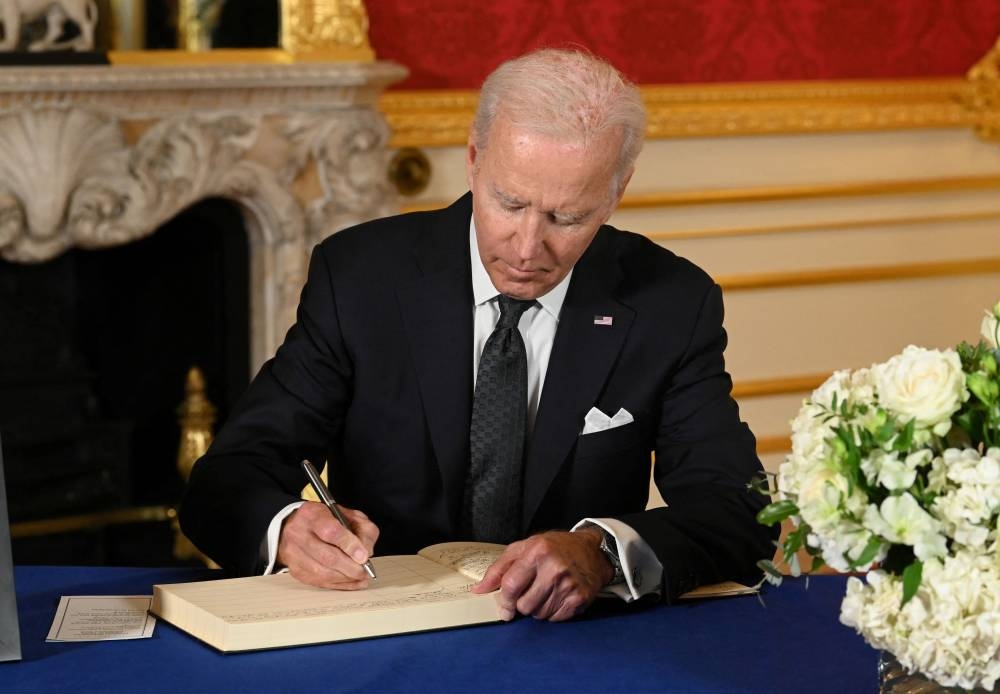 US President Joe Biden signs a book of condolence at Lancaster House in London, following the death of Queen Elizabeth II. — Reuters pic