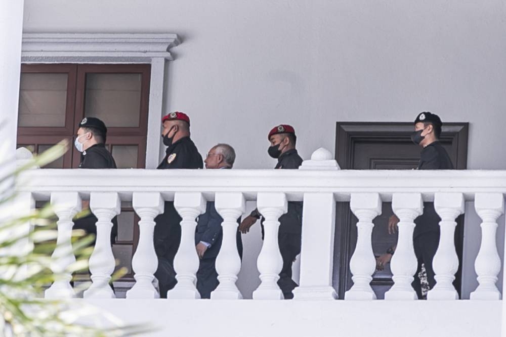 Former prime minister, Datuk Seri Najib Razak (center) escorted by Malaysian prison officers in the court corridor during the 1 Malaysia Development Berhad (1MDB) hearing case at Kuala Lumpur High Court September 26, 2022. — Picture by Hari Anggara