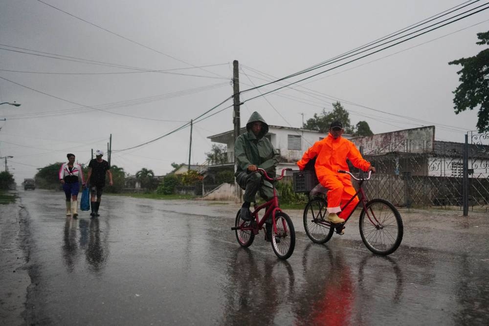 People walk under the rain ahead of the arrival of Hurricane Ian in Coloma, Cuba, September 26, 2022. — Reuters pic
