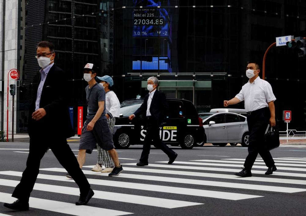 People pass by an electronic screen showing Japan's Nikkei share price index inside a commercial building in Tokyo September 22, 2022. — Reuters pic 