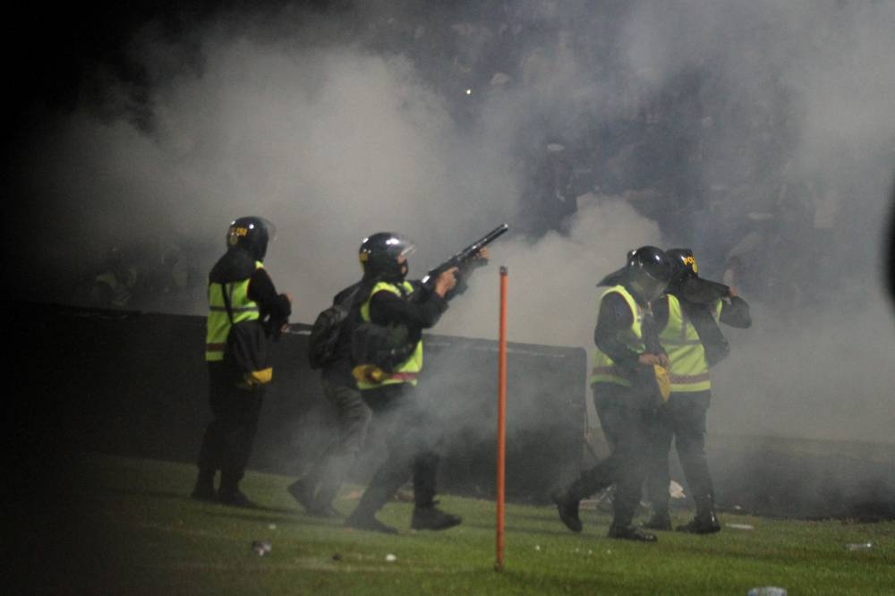 A riot police officer fires tear gas during a riot after the league BRI Liga 1 football match between Arema vs Persebaya at Kanjuruhan Stadium in Malang, East Java province, Indonesia, October 2, 2022, in this photo taken by Antara Foto. Antara Foto/Ari Bowo Sucipto/via Reuters