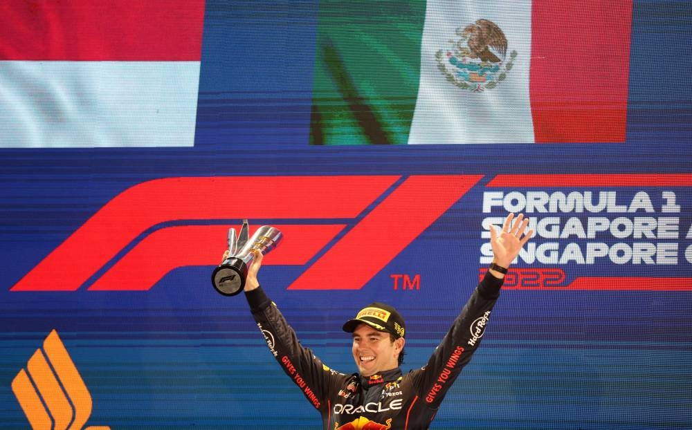 Red Bull's Sergio Perez celebrates with the trophy on the podium after winning the Singapore Grand Prix at the Marina Bay Street Circuit October 2, 2022. — Reuters pic