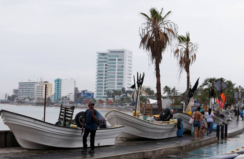 Um homem passa por barcos armazenados fora da água no calçadão enquanto o furacão Orlene se aproxima do balneário de Mazatlan, no Pacífico, no estado de Sinaloa, México, em 2 de outubro de 2022.  – Foto da Reuters