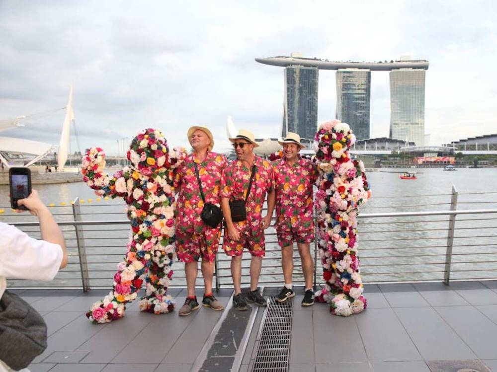 Performers for a roving act called Flower Men (far left and far right) posing for photos with Singapore Grand Prix attendees at the Marina Bay circuit park on October 2, 2022. — TODAY pic