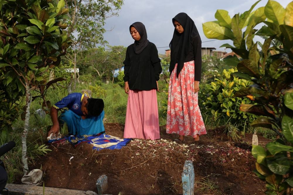 Children of Iwan Junaedi visit their father’s grave, who died after a riot and stampede at Kanjuruhan Stadium, following a football match between Arema vs Persebaya in Singosari, Malang, East Java province, Indonesia, October 3, 2022. — Reuters pic 