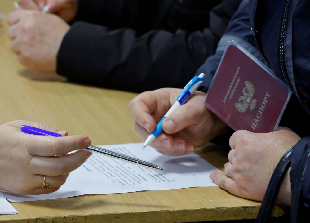 A voter fills in documents at a polling station during a referendum on the joining of the self-proclaimed Donetsk People's Republic (DPR) to Russia, in Donetsk, Ukraine September 27, 2022. — Reuters pic