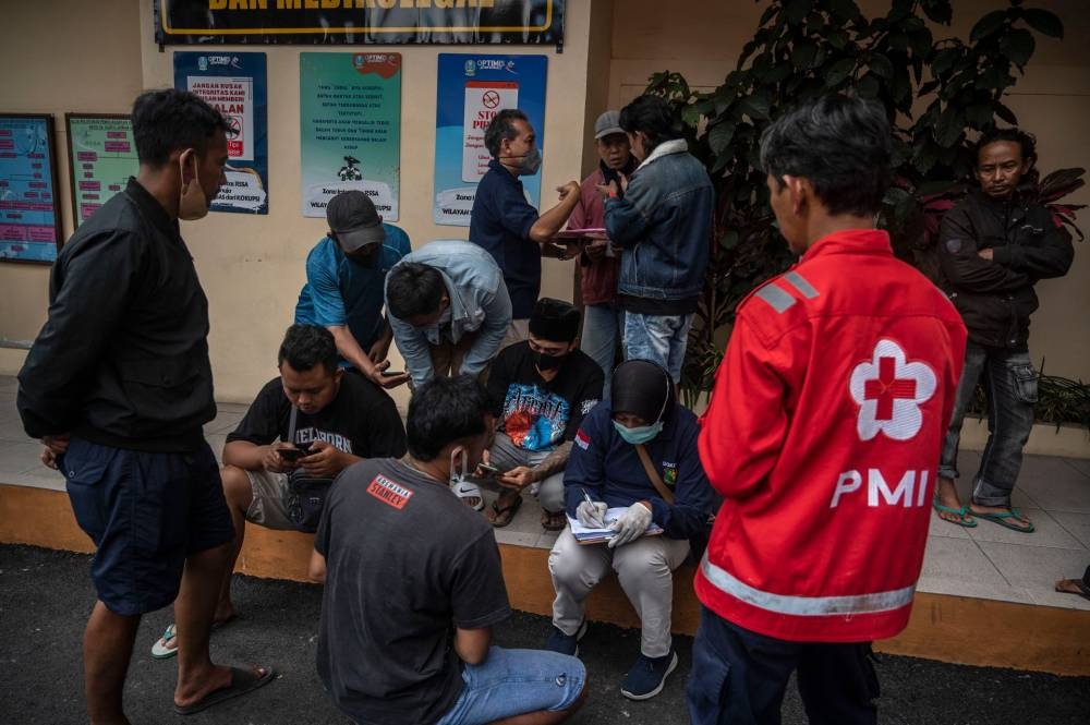 Relatives of victims wait outside a hospital in Malang, East Java on October 2, 2022.— AFP pic