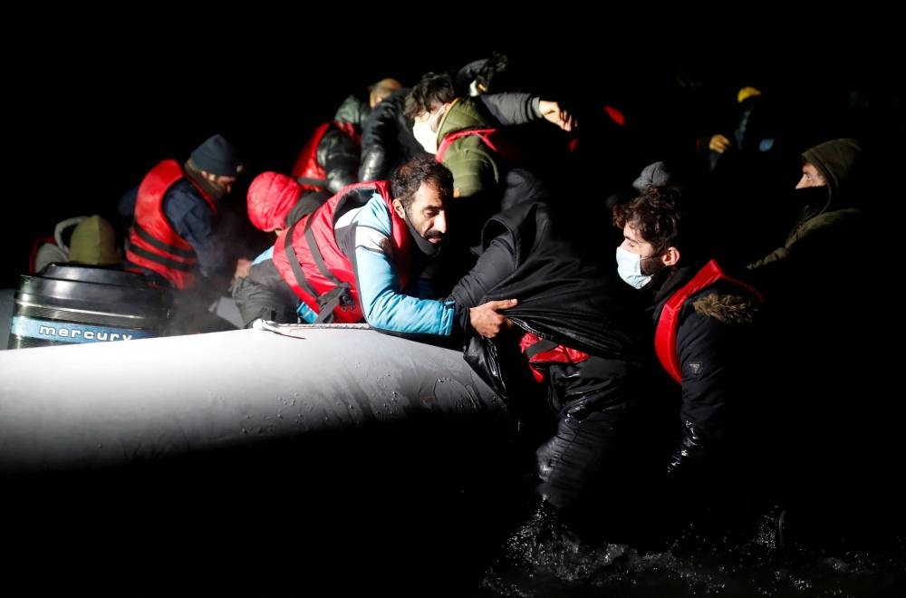 Migrants get on an inflatable dinghy as they leave the coast of northern France to cross the English Channel, in Wimereux near Calais, France, December 16, 2021. — Reuters file pic