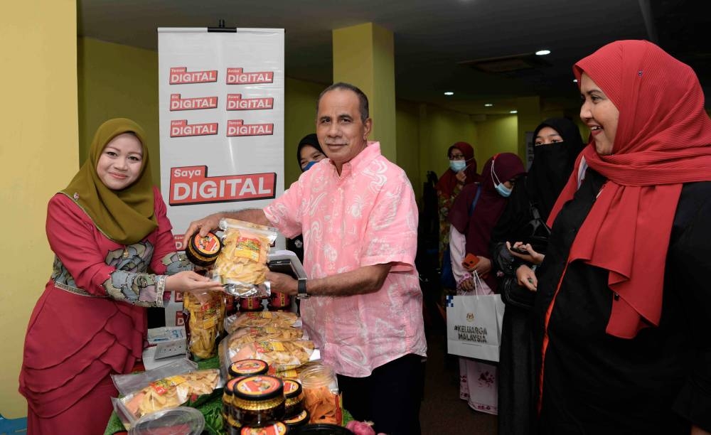 Felcra Berhad Board member Datuk Seri Ghazali Ibrahim (centre) looks at food products by Nur Shawani Che Mansur (left) at the Jelajah #SayaDigital Keluarga Malaysia programme organised by Malaysia Digital Economy Corporation (MDEC) in Padang Terap, Kuala Nerang October 4, 2022. — Bernama pic