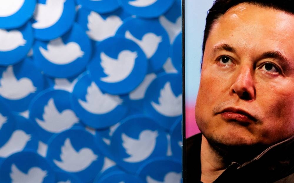 An image of Elon Musk is seen on a smartphone placed on printed Twitter logos in this picture illustration taken April 28, 2022. — Reuters pic