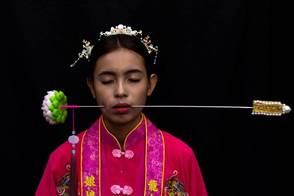 A medium woman with her mouth pierced is portrayed while in trance during the Jui Tui Shrine procession amidst celebrations of the annual vegetarian festival, observed by Taoist devotees from the Thai-Chinese community in the ninth lunar month of the Chinese calendar, in Phuket Town, Thailand October 2, 2022. — Reuters pic