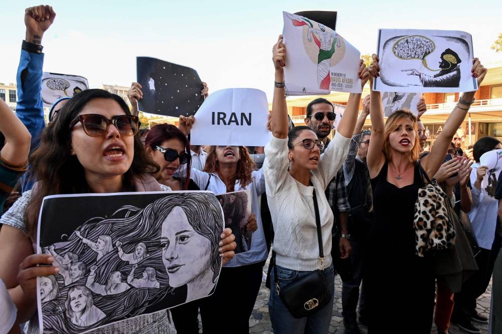  Women protest with placards during the unveiling of a banner on the facade of the town hall in support of the Iranians fighting for their freedom and against obscurantism in their country, in Montpellier, southern France October 3, 2022.  — AFP pic