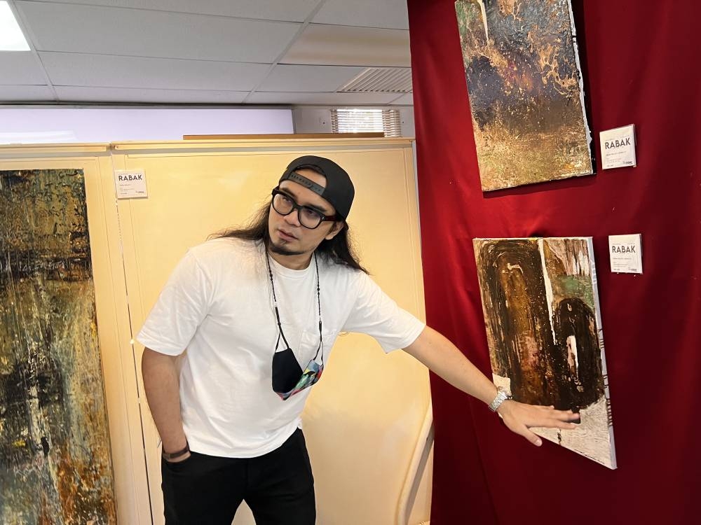Maizul Affendy explaining the emotions depicted in his abstract paintings to visitors at The Art Gallery Penang.