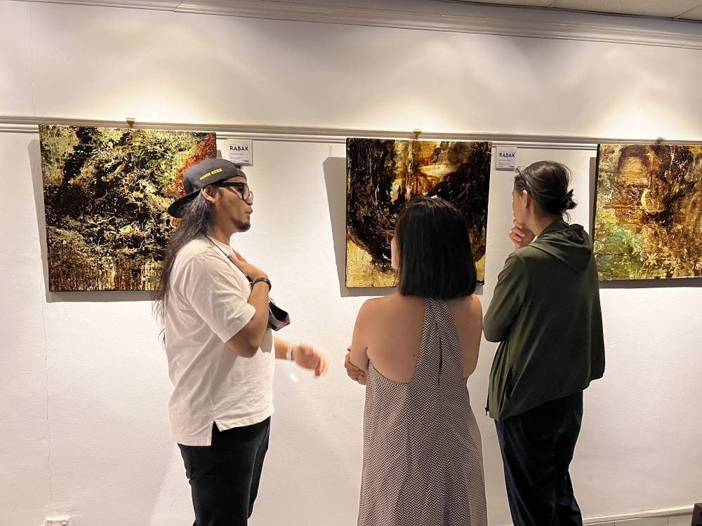Maizul Affendy (left) speaking to visitors at his solo exhibition.