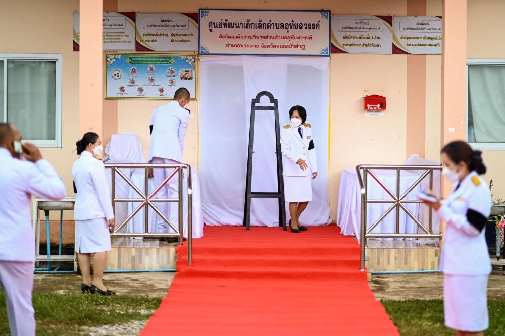 Officials prepare a red carpet leading to the nursery ahead of the arrival of Thailand's King Maha Vajiralongkorn in the northeastern Nong Bua Lam Phu province on October 7, 2022, the day after a former police officer killed at least 37 people in a mass shooting at the site. — AFP pic