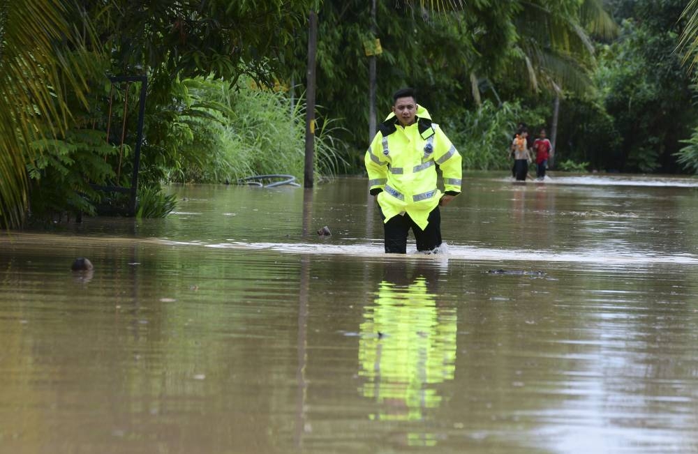 A police officer surveys the flood in Kampung Paya Kenangan in Johor Baru, October 5, 2022. — Bernama pic 