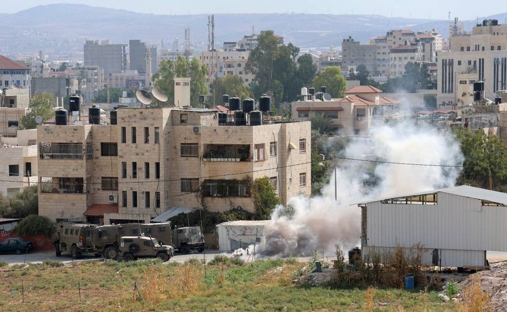 Smoke billows around Israeli security forces vehicles during a reported operation in Jenin city in the occupied West Bank, on October 8, 2022. — AFP pic