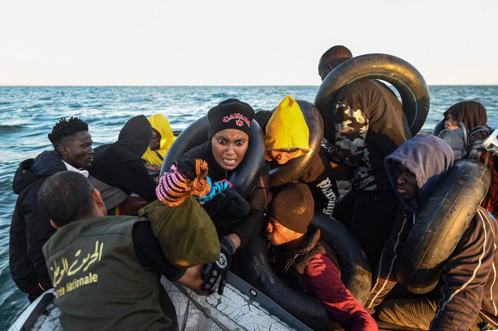 Migrants from sub-Saharan Africa sit in a makeshift boat that was being used to clandestinely make its way towards the Italian coast, as they are found by Tunisian authorities about 50 nautical miles in the Mediterranean sea off the coast of Tunisia’s central city of Sfax on October 4, 2022. — AFP pic