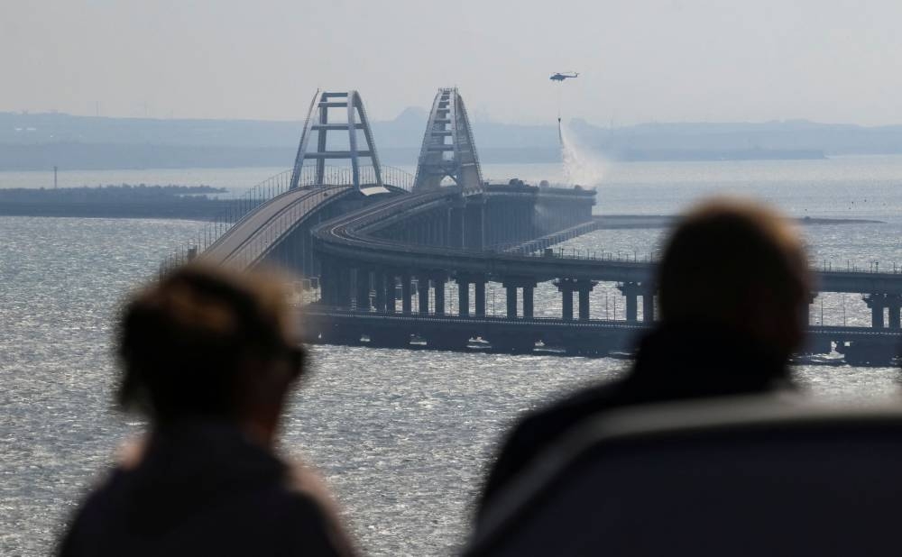 People watch fuel tanks ablaze on the Kerch bridge in the Kerch Strait, Crimea, October 8, 2022. — Reuters pic