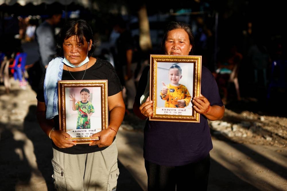 Nhooprom Kotprathum and Boonthom Piamool hold up pictures of their grandson Tanakorn Karadee (4) at the Wat Rat Samakee temple, following a mass shooting in the town of Uthai Sawan, Nong Bua Lam Phu province, Thailand, October 8, 2022. — Reuters pic