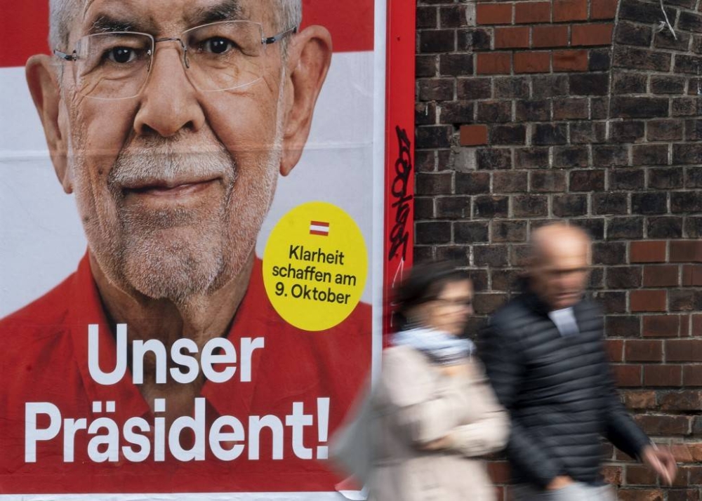 In this file photo taken on October 3, 2022 People walk past an election poster featuring Austria's President Alexander Van der Bellen, in Vienna. Austrians vote on October 9, 2022 in presidential elections expected to return the incumbent seen as a beacon of stability as the Alpine EU member struggles with an energy crisis and inflation. — AFP pic