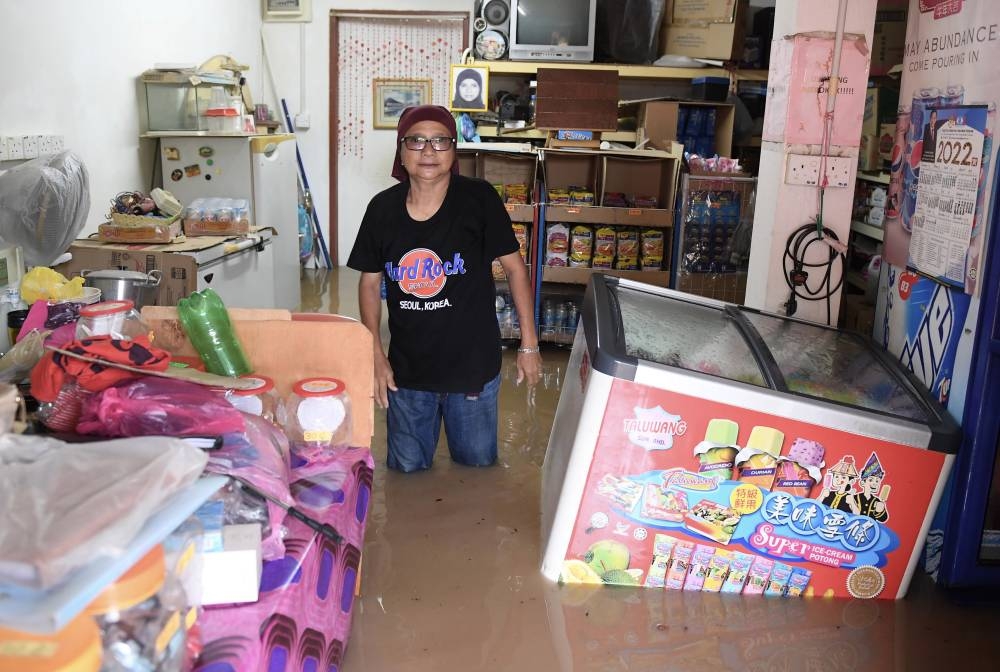 A resident of Kampung Ketiau wades in flood water at her shop, in Kota Kinabalu October 10, 2022. — Bernama pic 