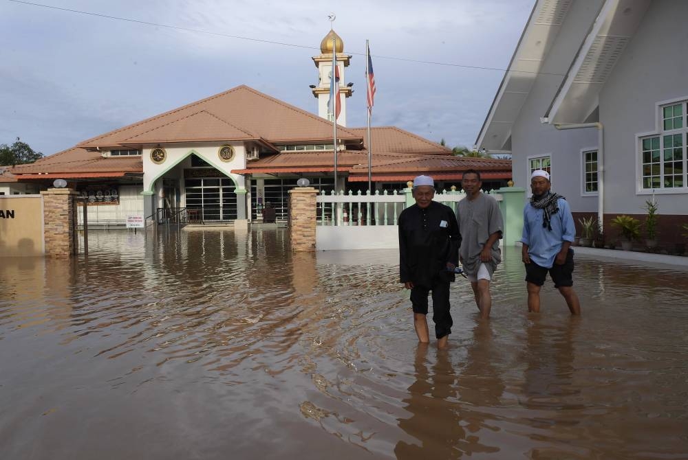 Residents of Kampung Ketiau wade in flood water outside the Kampung Ketiau Mosque in Kota Kinabalu October 10, 2022. — Bernama pic