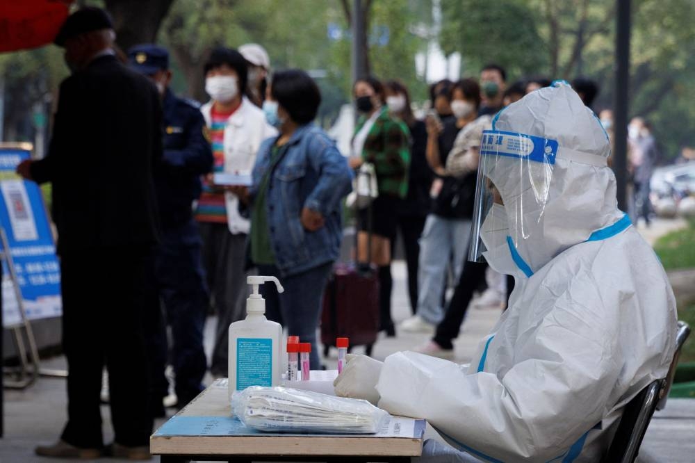 People line up to get a swab at a nucleic acid testing station set up to trace possible Covid-19 outbreaks in Beijing October 7, 2022. — Reuters pic