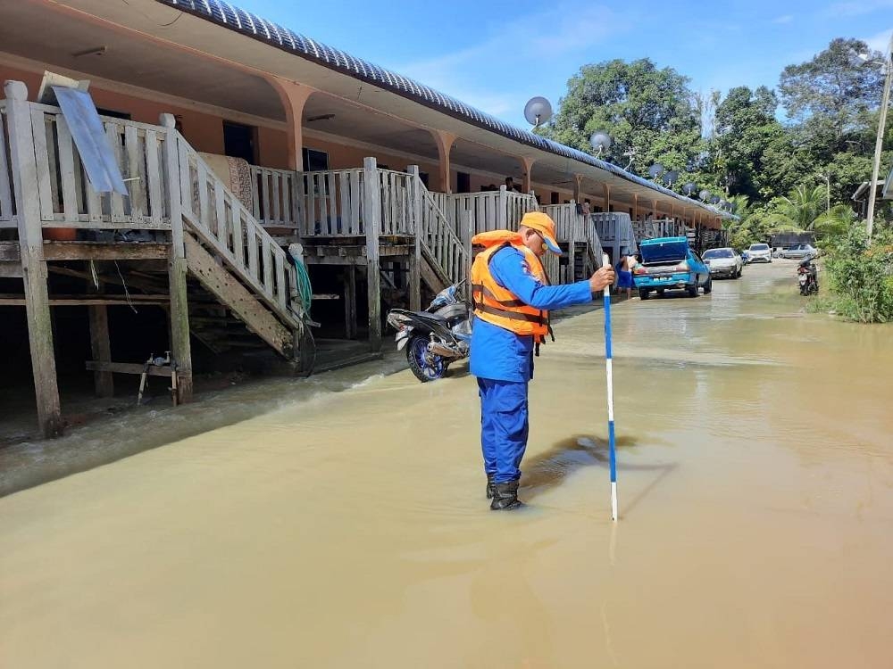 An APM personnel checks the flood level at Rumah Richard, Saeh on Monday. — Borneo Post Online pic