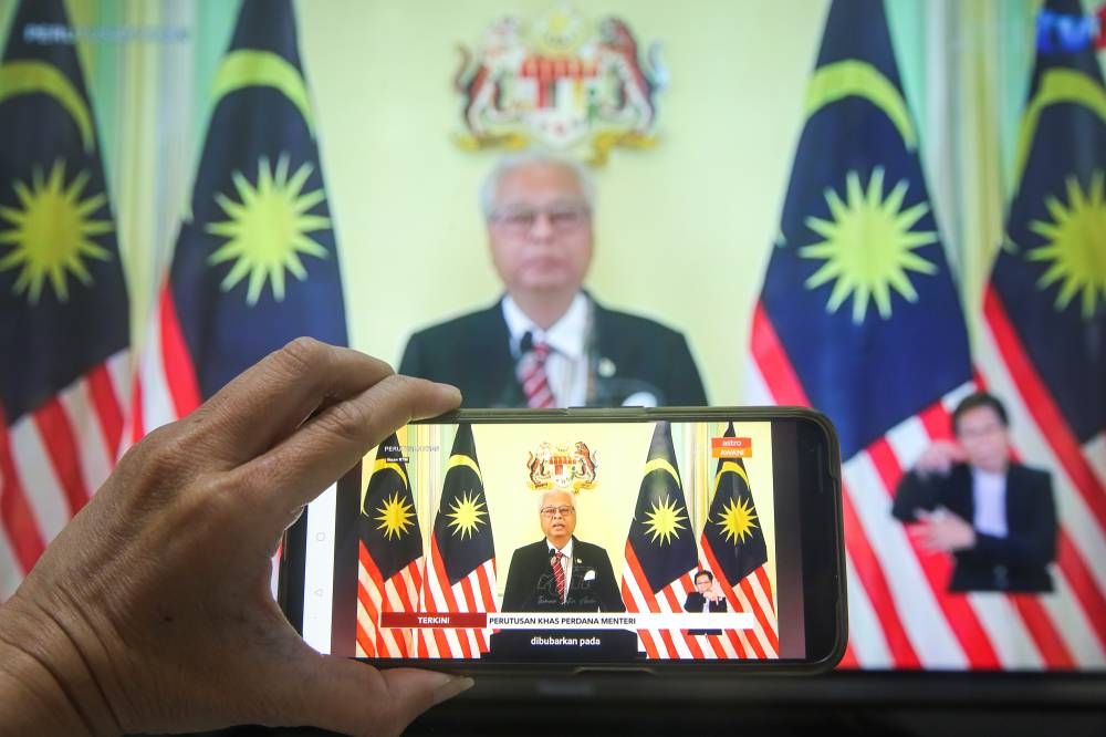 A live broadcast of Prime Minister Datuk Seri Ismail Sabri Yaakob is seen on a handphone screen and television in Selangor October 10, 2022. — Picture by Choo Choy May