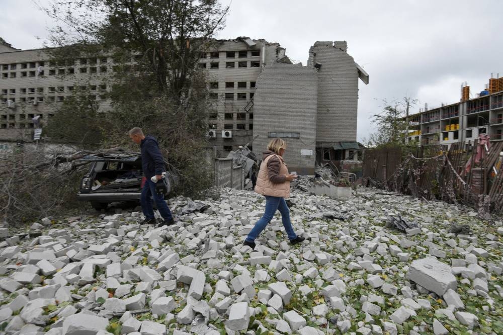 Local residents walk at a site of a building damaged by a Russian missile strike, amid Russia's attack on Ukraine, in Dnipro, Ukraine October 10, 2022. ― Reuters pic