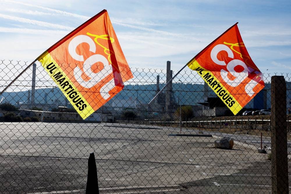 Flags of CGT union are displayed as people gather during a TotalEnergies and Esso ExxonMobil workers' protest outside TotalEnergies refinery in La Mede, France October 11, 2022. — Reuters pic