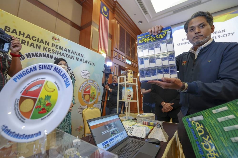 Health Minister Khairy Jamaluddin shows the sugar content in drinks after launching the Putrajaya Anti-Obesity Seminar and Trim&Fit Weight Management Module programme in Putrajaya, October 12, 2022. — Bernama pic 