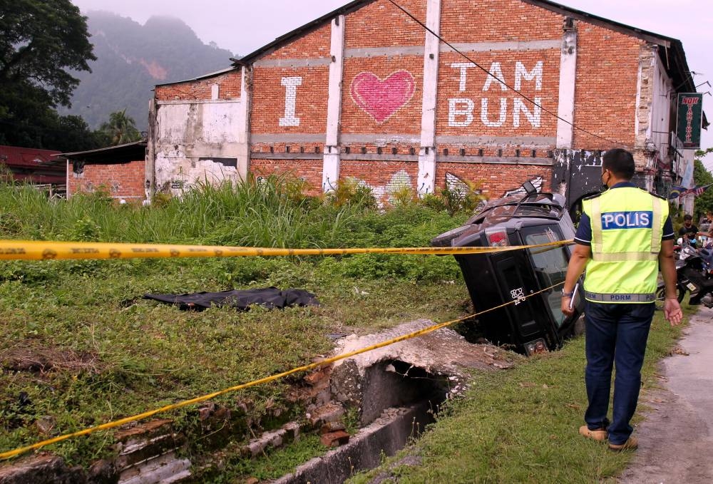 Police personnel conduct an investigation around the location where a woman’s body was found near the traffic light junction at Jalan Tambun, Ipoh, October 12, 2022. — Bernama pic 