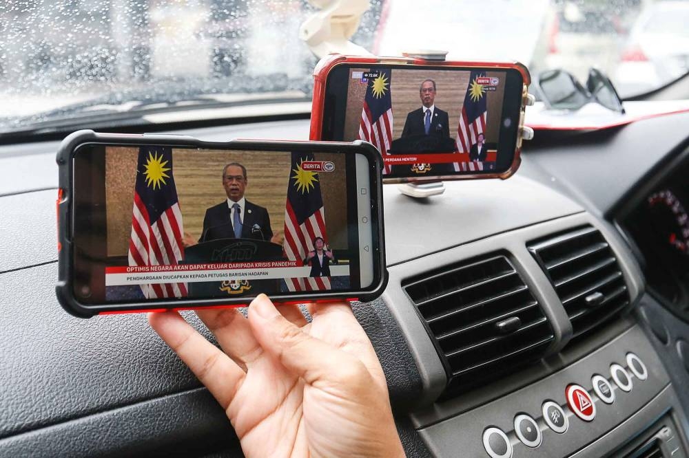 A woman watches a live telecast of Prime Minister Tan Sri Muhyiddin Yassin and the Cabinet announcing their resignation in Bayan Baru, Penang, August 16, 2021. — Picture by Sayuti Zainudin