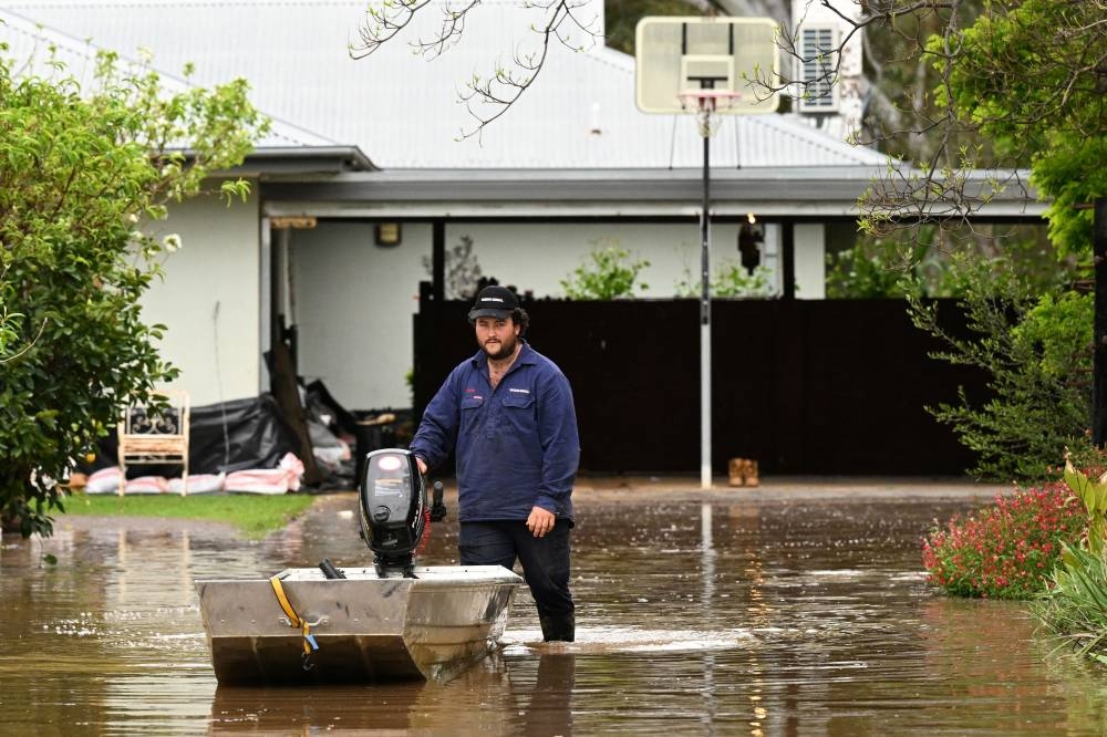 A man pushes a boat as floodwaters inundate a Victorian residential area amidst evacuation orders in Rochester, Australia October 14, 2022. ― AAP Image/James Ross via Reuters