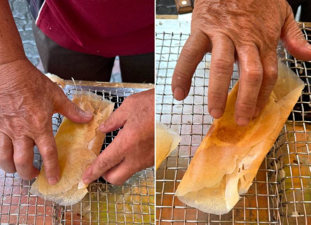 The 'apom' is folded in the middle once it is placed on a wire rack . He presses it to ensure the fold for the crepe holds (right).