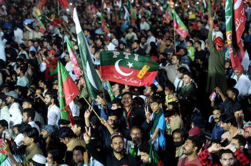 Supporters of Pakistan’s former prime minister Imran Khan listen to their leader’s speech during a by-election campaign meeting in Karachi on October 14, 2022. ― AFP pic