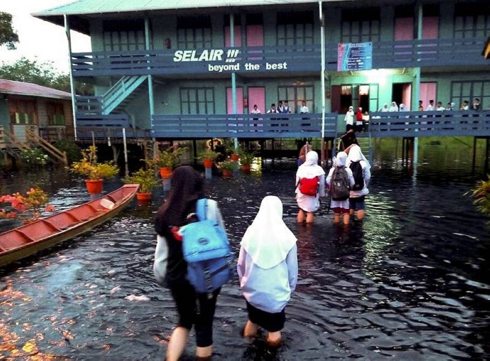 Students wade through flood waters to get to their classrooms at Sekolah Kebangsaan Orang Kaya Selair in Matu, Sarawak February 6, 2018. — Bernama pic