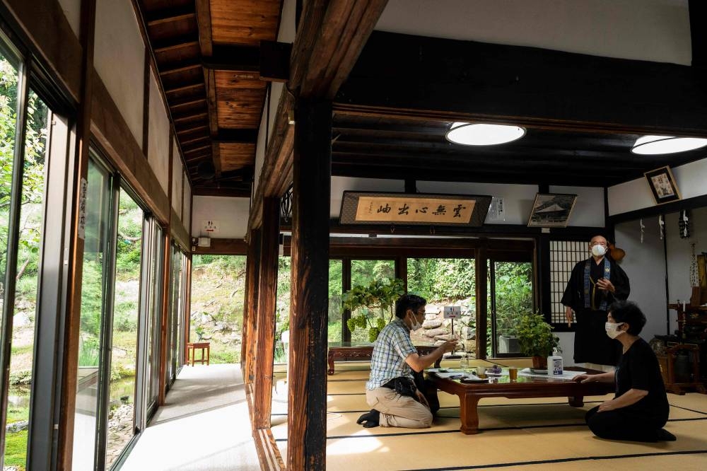 Buddhist monk Tesshu Inoue walks past visitors at a building next to Daizenji temple. — AFP pic