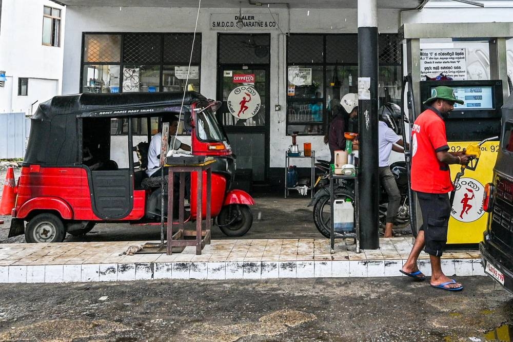 An employee fills petrol in an auto rickshaw at Ceylon petroleum corporation fuel station in Colombo on October 17, 2022. Crisis-hit Sri Lanka slashed fuel prices today after the World Bank warning that the economy will shrink an unprecedented 9.2 per cent this year. — AFP pic