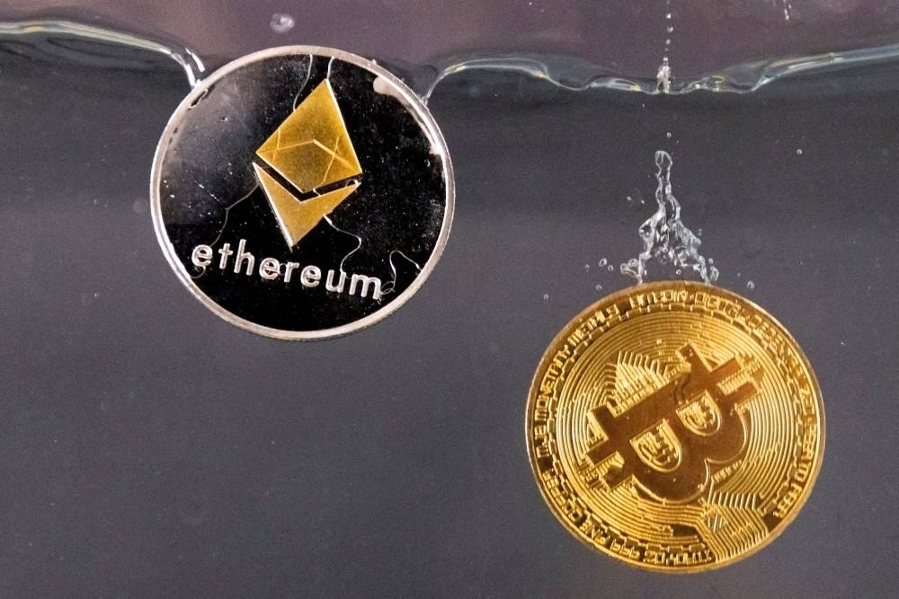  Souvenir tokens representing cryptocurrency Bitcoin and the Ethereum network, with its native token ether, plunge into water in this illustration taken May 17, 2022. — Reuters pic