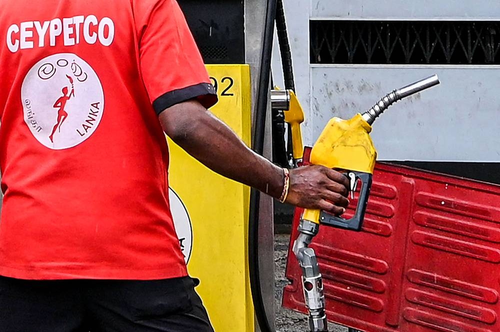 An employee fills petrol in an auto rickshaw at Ceylon petroleum corporation fuel station in Colombo on October 17, 2022. — AFP pic