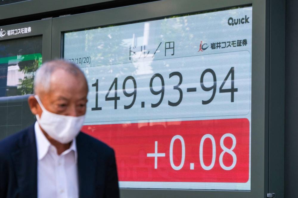 A man walks past an electronic quotation board displaying the yen's rate against the US dollar in Tokyo on October 20, 2022. — AFP pic